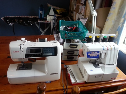 My sewing machines, tucked into a corner of my work table. Behind is a small set of drawers and a tray that contain scissors, quick unpick, pins, and all the other rapid-access stuff. 